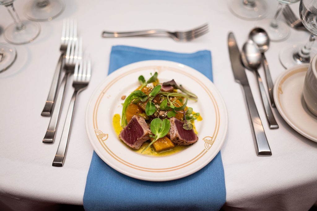 A tuna dish sits at a table setting ahead of dinner service.